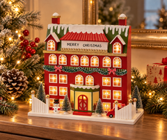 Diorama Casetta Natalizia LED in legno H33 cm EDG Enzo De Gasperi Exclusive ambientato su una madia in legno, con finestre illuminate, abeti innevati, ghirlande e decorazioni natalizie con luci calde.